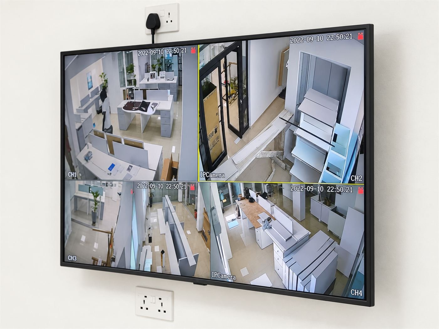 A wall-mounted CCTV monitor displaying a live four-camera office feed, installed by Truthsol Limited